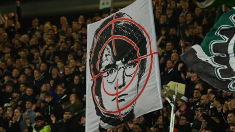 Hannover-Fans halten ein Fadenkreuz-Plakat mit dem Gesicht des Film-Zauberers Harry Potter hoch.