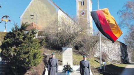 Zwei Soldaten standen am Kriegerdenkmal vor der Pfarrkirche St. Elisabeth. Am Denkmal war ein Blumengesteck abgelegt worden. 