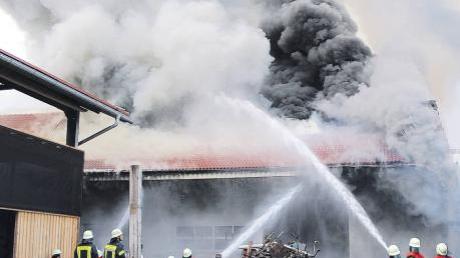Einsatzkräfte der Feuerwehren versuchen, die brennende Werkstatt des Bauernhofes zu löschen.  