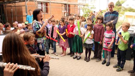 Die Schulkinder sangen unter der Leitung von Lehrerin Anna Ruf (links) zur Hebauffeier der Kinderkrippe ein Lied. Josefine Götzschel aus der Klasse 2a (im Strickkleid vor dem Jugendlichen) sagte ein Gedicht auf. 
