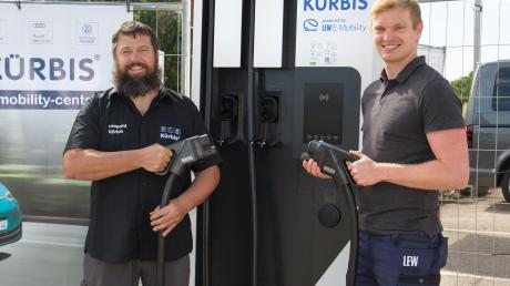 Leopold Kürbis, Geschäftsführer des gleichnamigen Autohauses (links), und Christoph Sturm, Projektmanager E-Mobility bei LEW, nehmen die neue Gleichstrom-Schnellladestation für E-Autos in Betrieb. 	