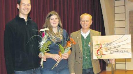 Heinz Anderle (rechts) bedankte sich bei Anna-Lena Christi und Tobias Schneider für ihr Engagement. Schneider hat die Tafel geschnitzt, die künftig bei Umzügen des Jugendblasorchesters vorangetragen wird.  