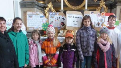 Stolz präsentieren einige Kinder mit Kerstin Müller (links) ihre selbst gestalteten Wegweiser mit den zehn Geboten in der Biberbacher Kirche.