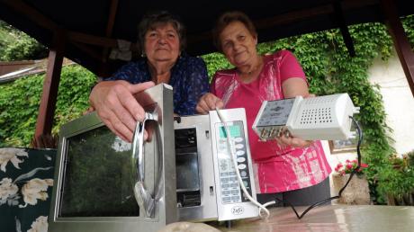 Elke Schwägerl (links) und Gerlinde Wanke zeigen einige ihrer Elektrogeräte, die infolge der Überspannung in der Stromleitung kaputt gegangen sind. 
