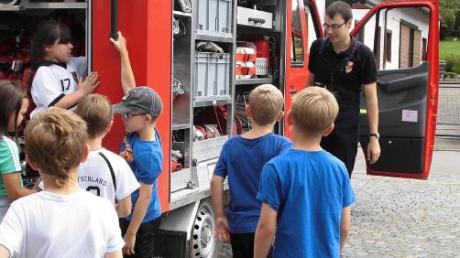 Michael Rößle von der Eppishofer Feuerwehr erklärt den Kindern die Teile des Feuerwehrautos.  

