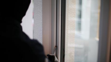 Ein Einbrecher versucht über das Fenster in ein Haus zu gelangen.