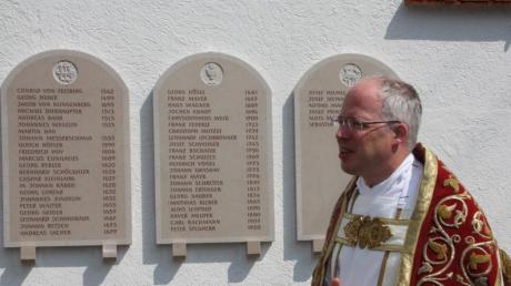 Fischachs Pfarrer Sebastian Nößner blickt auf die lange Reihe seiner Vorgänger zurück. Sein eigener Name ist auch schon eingemeißelt. 	