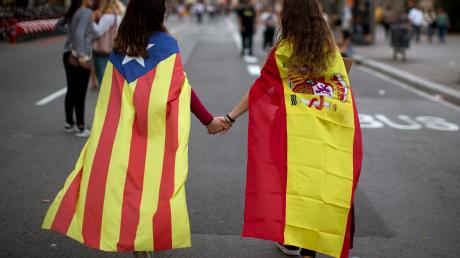 Zwei junge Frauen, in die spanische Nationalflagge (rechts) sowie die katalanische Flagge «Estelada» gehüllt, sind in Barcelona auf dem Weg zu einer Demonstration gegen die Polizeigewalt gegenüber den Wählern. 