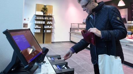 Bei der Metzgerei Hörmann in Aystetten kassiert ein Zahlautomat die Wurst ab. Kundin Ursule Wittmann führt es vor: Rechnung scannen, Geldschein einlegen, Wechselgeld kassieren.