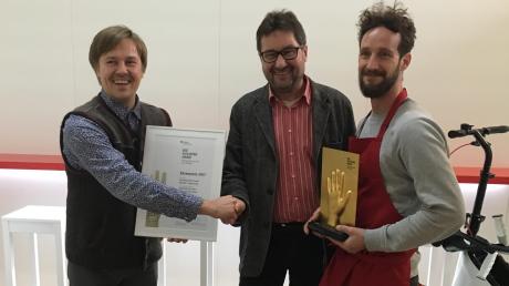 Der Geschäftsführer von Orthoscoot, Andreas Hertle (links), nahm den BGHW-Preis von Martin Kümmerlin entgegen. Mit im Bild ist Martin Band von der Serviceleitung der Firma.  	 	