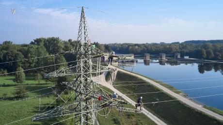 Monteure sind auf einen Strommast am Wasserkraftwerk Ellgau geklettert. Sie erneuern dort die 110-Kilovolt-Stromleitungen.