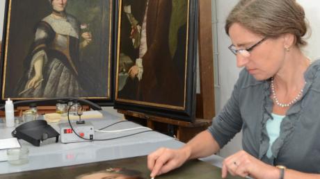 In der Restaurierungswerkstatt der Kunstsammlungen Augsburg werden die Gemälde aus dem Depot für den Ausstellungsbetrieb fertig gemacht: Restauratorin Maria Winner reinigt die Oberfläche eines Bildes mit einem Wattestäbchen. 
