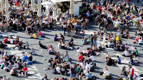 Viele Augsburger zieht es bei Sonnenschein an den Rathausplatz – die Jüngern setzen sich gerne auf den Boden, die älteren Besucher bevorzugen schon eher einen Sitzplatz in einem Lokal. 
