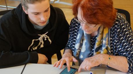 Schüler Moritz Eger hilft Rentnerin Isabella Schuster bei der Erstellung einer Whatsapp-Gruppe. 