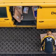 Eine Mitarbeiterin der Deutsche Post DHL belädt ihr Fahrzeug. 