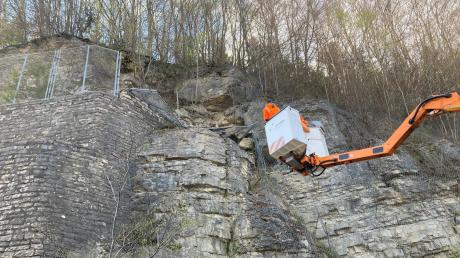 Experten der Autobahn GmbH Niederlassung Südwest untersuchen  mit einem Hubwagen einen Felsen über der Autobahn 8.