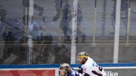 Eishockeyspieler spiegeln sich vor leeren Rängen in der Bande.