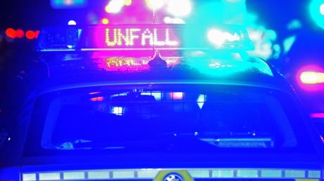Ein Streifenwagen der Polizei steht mit Blaulicht an einer Unfallstelle.