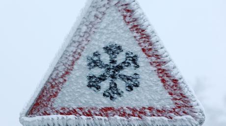 Ein vereistes Verkehrszeichen weist auf winterliche Straßenverhältnisse hin. Gerade jetzt ist Vorsicht geboten. 