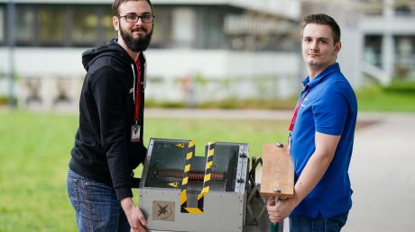 Marvin Schmauder (r) und Jacob Herdtweck halten im Karlsruher Institut für Technologie (KIT) beim Landeswettbewerb «Jugend forscht» ein Besenreinigungsgerät in den Händen.