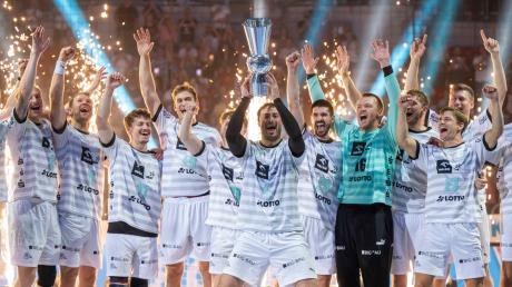 Kiels Domagoj Duvnjak reckt den Pokal nach oben, während seine Mitspieler feiern.
