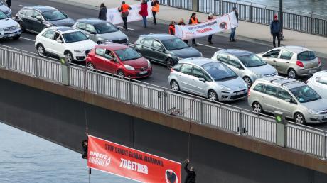 Zwei Klimaaktivisten seilen sich mit einem Banner mit der Aufschrift «Stop deadly global warming - together» von der Europabrücke zwischen dem deutschen Kehl und dem französischen Straßburg ab.