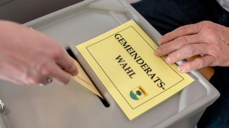 Ein Mann gibt im Wahllokal seinen Stimmzettel zur Gemeinderatswahl ab.