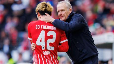 Freiburgs Trainer Christian Streich (r) spricht mit Freiburgs Ritsu Doan (l) nach seiner Auswechslung.