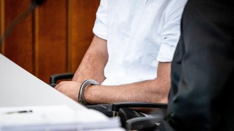 Der Angeklagte sitzt mit Handschellen in einem Gerichtssaal des Landgerichts Heilbronn.