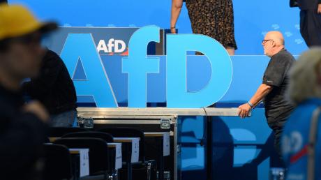 Helfer schieben nach der AfD Europawahlversammlung das AfD Logo aus der Messehalle.