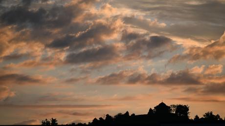 Von der aufgehenden Sonne rot angestrahlt werden Wolken über dem Württemberg bei Stuttgart.
