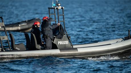 Einsatzkräfte der Polizei fahren auf einem Boot.