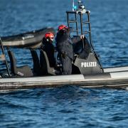Einsatzkräfte der Polizei fahren auf einem Boot.