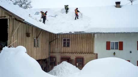 Schwere Schneelast: Die Feuerwehr schaufelt in Sulzberg (Landkreis Oberallgäu) das Dach eines Bauernhofes frei.  	