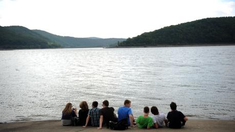 Schülerinnen und Schüler auf Klassenfahrt sitzen am Ufer des Edersees in Hessen.