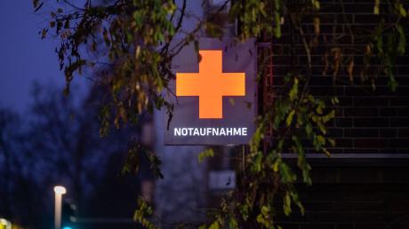 Ein Schild mit einem roten Kreuz hängt an der Notaufnahme eines Krankenhauses.