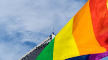Eine Regenbogenfahne weht vor der Kirche St. Christophorus am Rande der Segnung queerer Menschen.