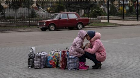 Eine Mutter umarmt ihre Tochter, während sie auf einen Bus warten, um aus der Stadt Slowjansk zu fliehen.