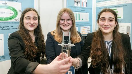 Die Chemie-Bundessiegerinnen Lena Fries (l-r), Hannah Amrhein und Hanna Fries halten ihr Forschungswerkzeug, ein Becherglas mit Elektroden.