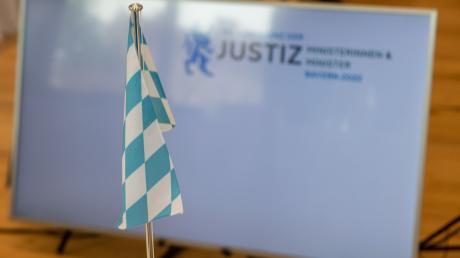 Bei der Justizministerkonferenz ist die bayerische Landesflagge vor einem Bildschirm zu sehen.