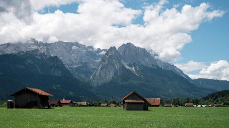 Auf den Wiesen vor dem Alpenmassiv bei Garmisch-Patenkirchen stehen mehrere Scheunen.