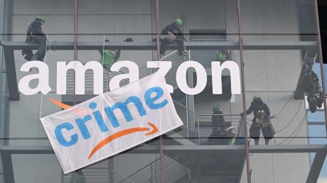 Greenpeace-Aktive hängen während der Rabattaktion Black Friday ein Plakat mit der Aufschrift «crime» am Amazon Deutschland Gebäude auf.