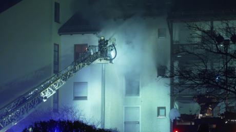 Feuerwehrleute im Einsatz bei einem Brand in einem Mehrfamilienwohnhaus.