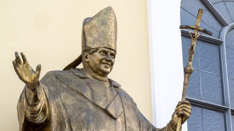 Eine Figur des früheren Papstes Benedikt XVI. hängt an einer Fassade am Kapellenplatz im Zentrum von Altötting.