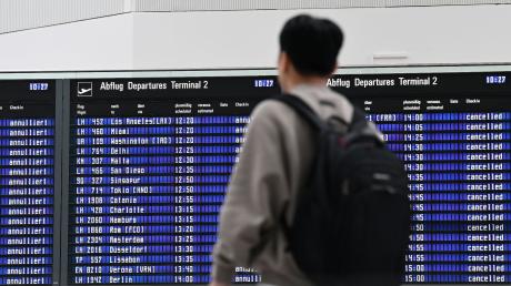 Ein Passagier steht im Münchner Flughafen vor der Anzeigentafel.
