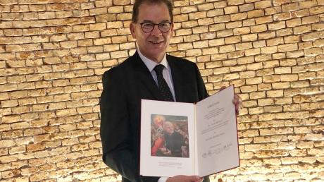 Gerd Müller, ehemaliger Bundesentwicklungsminister, hält die Eugen-Biser-Preis-Auszeichnung in den Händen.