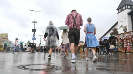 Besucher gehen bei Regenwetter über die Theresienwiese.