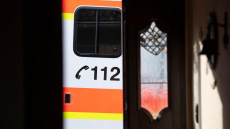 Ein Rettungswagen parkt vor der geöffneten Tür eines Wohnhauses.