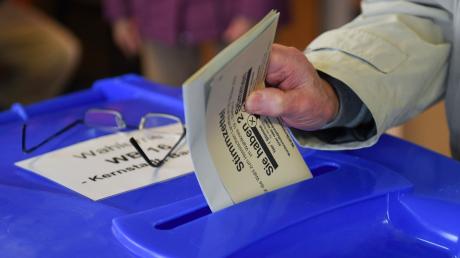 Eine Wählerin gibt in einem Wahllokal ihren Stimmzettel ab.