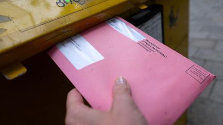 Eine Frau wirft einen Wahlbrief für die Landtags- und Bezirkswahlen in einen Briefkasten.